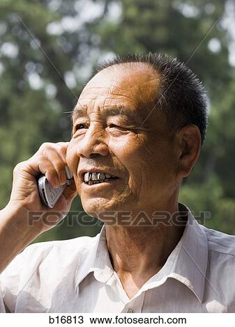 Stock Image - Man talking on cell phone outdoors smiling. Fotosearch