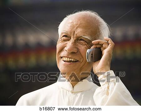 Stock Photo - Man talking on cell phone outdoors smiling. Fotosearch