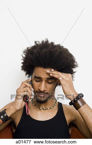 Man with afro and bracelets talking on cell phone with hand on head View Large Photo Image Stock Photo - Man with afro and bracelets talking on cell phone with hand on head. Fotosearch