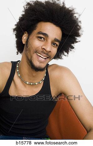 Man with afro sitting on chair smiling View Large Photo Image Stock Photo - Man with afro sitting on chair smiling. Fotosearch