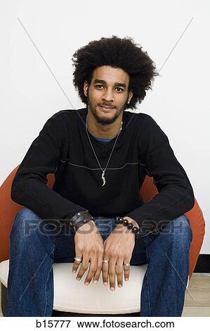 Man with afro sitting on chair View Large Photo Image Stock Photo - Man with afro sitting on chair. Fotosearch