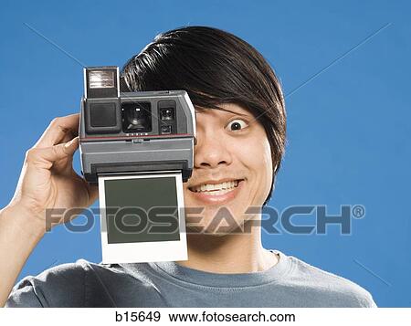 Stock Photo - Man with instant camera and blank photo. Fotosearch
