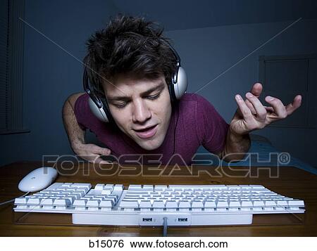 Man with keyboard and headphones playing air guitar View Large Photo Image Stock Photograph - Man with keyboard and headphones playing air guitar. Fotosearch