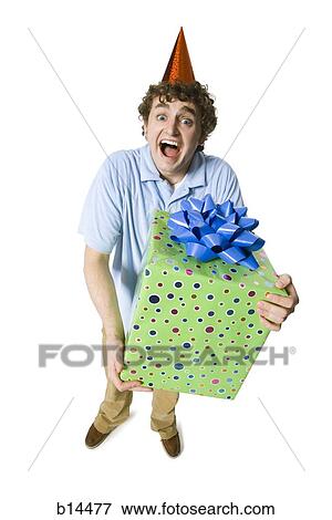 Man with party hat holding gift box smiling View Large Photo Image Stock Photo - Man with party hat holding gift box smiling. Fotosearch