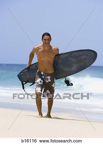 Stock Photograph - Man with surfboard on beach smiling. Fotosearch