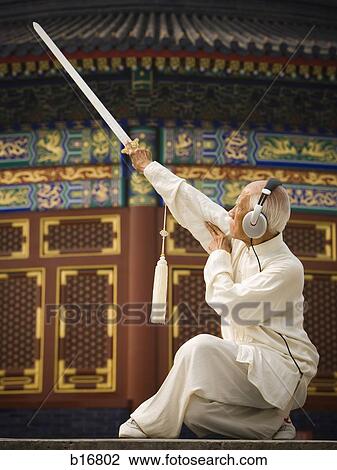 Man with sword doing Kung Fu with headphones View Large Photo Image Stock Image - Man with sword doing Kung Fu with headphones. Fotosearch