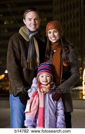 Stock Image - Man with woman and girl standing outdoors in winter smiling. Fotosearch