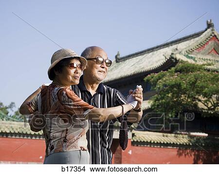 Mature couple dancing outdoors with blue sky and pagoda in background View Large Photo Image Picture - Mature couple dancing outdoors with blue sky and pagoda in background. Fotosearch