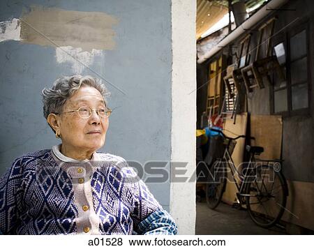 Mature woman sitting with bicycle in background View Large Photo Image Stock Photo - Mature woman sitting with bicycle in background. Fotosearch