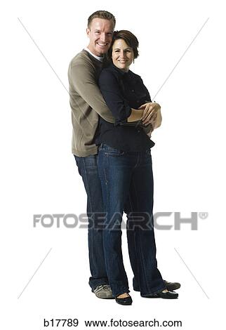 Mid adult couple standing with his arms around her. View Large Photo Image Stock Photo - Mid adult couple standing with his arms around her.. Fotosearch
