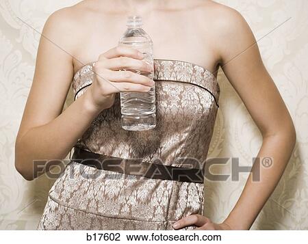Mid section view of woman in dress holding bottled water View Large Photo Image Stock Image - Mid section view of woman in dress holding bottled water. Fotosearch