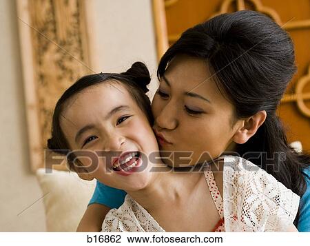 Mother giving daughter a kiss on cheek View Large Photo Image Stock Image - Mother giving daughter a kiss on cheek. Fotosearch