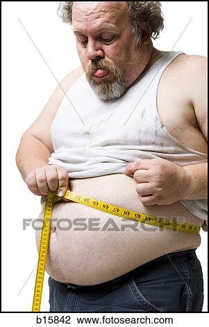 Stock Image - Obese man measuring waist with tape measure. Fotosearch