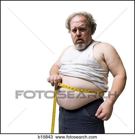 Stock Image - Obese man measuring waist with tape measure. Fotosearch