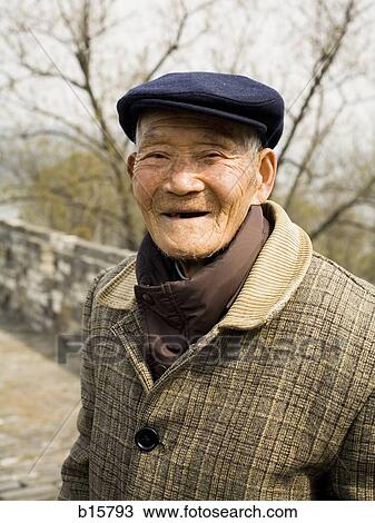 Stock Image - Old man with hat standing outdoors smiling. Fotosearch