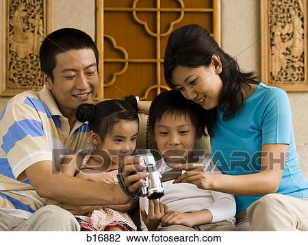 Parents looking at video recorder with son and daughter View Large Photo Image Stock Image - Parents looking at video recorder with son and daughter. Fotosearch