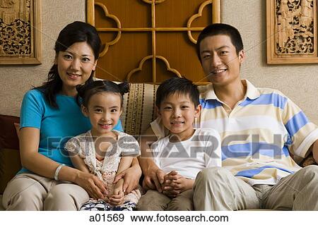 Parents with two children sitting on sofa smiling View Large Photo Image Stock Photo - Parents with two children sitting on sofa smiling. Fotosearch