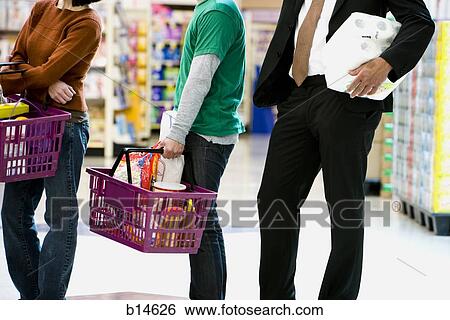 People waiting in line with shopping baskets at grocery store View Large Photo Image Stock Photograph - People waiting in line with shopping baskets at grocery store. Fotosearch