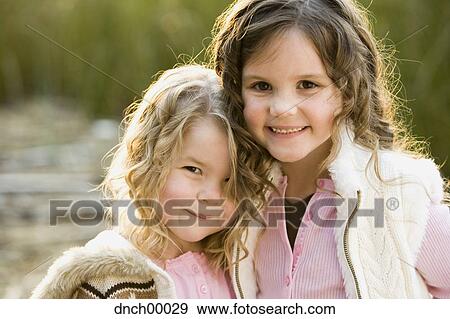 Portrait of two girls smiling and hugging outdoors View Large Photo Image Stock Photo - Portrait of two girls smiling and hugging outdoors. Fotosearch