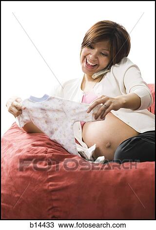 Pregnant Woman holding baby clothing. View Large Photo Image Stock Image - Pregnant Woman holding baby clothing.. Fotosearch