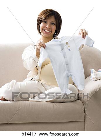 Pregnant Woman holding baby clothing. View Large Photo Image Stock Photo - Pregnant Woman holding baby clothing.. Fotosearch