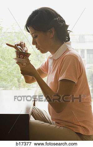 Profile of a woman sitting cross legged in front of large window with tea View Large Photo Image Stock Photo - Profile of a woman sitting cross legged in front of large window with tea. Fotosearch