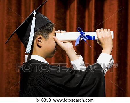Profile of boy graduate with mortar board looking through diploma View Large Photo Image Stock Photo - Profile of boy graduate with mortar board looking through diploma. Fotosearch