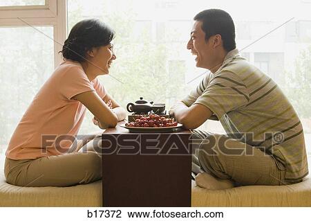 Profile of couple sitting cross legged with tea and fruit with large window in background View Large Photo Image Stock Image - Profile of couple sitting cross legged with tea and fruit with large window in background. Fotosearch
