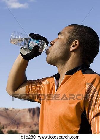 Profile of man drinking bottled water outdoors View Large Photo Image Stock Image - Profile of man drinking bottled water outdoors. Fotosearch
