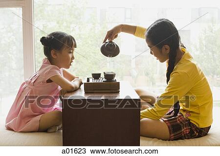 Profile of two girls sitting cross legged having tea View Large Photo Image Stock Image - Profile of two girls sitting cross legged having tea. Fotosearch