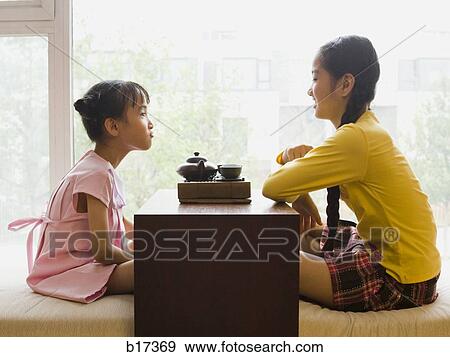 Profile of two girls sitting cross legged having tea View Large Photo Image Stock Photo - Profile of two girls sitting cross legged having tea. Fotosearch