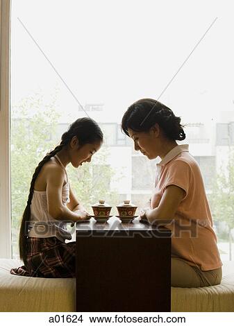 Profile of woman and girl sitting cross legged in front of large window View Large Photo Image Picture - Profile of woman and girl sitting cross legged in front of large window. Fotosearch