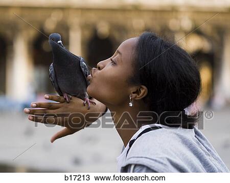 Profile of woman kissing pigeon perched on hand View Large Photo Image Stock Image - Profile of woman kissing pigeon perched on hand. Fotosearch