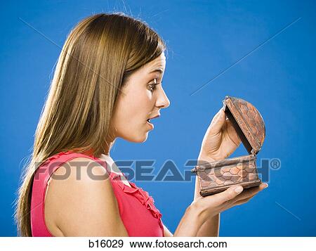 Stock Photo - Profile of woman looking in wooden box surprised. Fotosearch