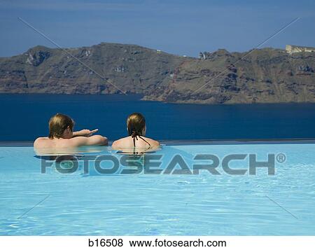 Rear view of couple in infinity pool with mountains View Large Photo Image Stock Photo - Rear view of couple in infinity pool with mountains. Fotosearch