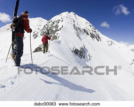 Rear view of two people with ski poles and snowboard on snowy mountain View Large Photo Image Stock Image - Rear view of two people with ski poles and snowboard on snowy mountain. Fotosearch