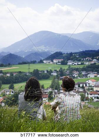 Rear view of two women on hill with village below View Large Photo Image Stock Photo - Rear view of two women on hill with village below. Fotosearch