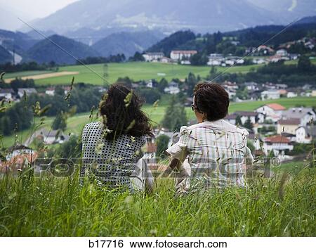 Rear view of two women on hill with village below View Large Photo Image Stock Photograph - Rear view of two women on hill with village below. Fotosearch