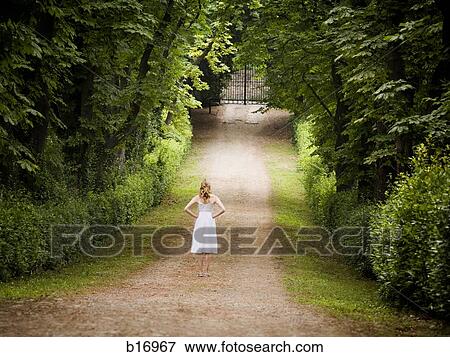 Rear view of woman on path in woods with iron gate View Large Photo Image Stock Photo - Rear view of woman on path in woods with iron gate. Fotosearch