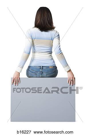 Stock Photo - Rear view of woman sitting on blank sign. Fotosearch