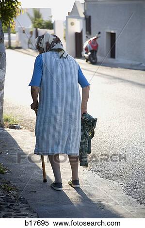 Rear view of woman with cane and head scarf walking down street View Large Photo Image Stock Photography - Rear view of woman with cane and head scarf walking down street. Fotosearch