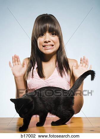 Stock Image - Scared woman with black kitten. Fotosearch