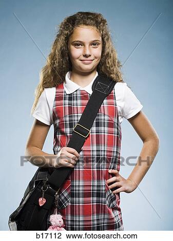 Stock Image - Schoolgirl standing with school bag smiling. Fotosearch