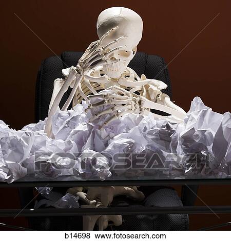Skeleton sitting at desk with crumpled papers View Large Photo Image Stock Photo - Skeleton sitting at desk with crumpled papers. Fotosearch