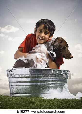 Smiling boy hugging and bathing dog outdoors on cloudy day View Large Photo Image Stock Photo - Smiling boy hugging and bathing dog outdoors on cloudy day. Fotosearch