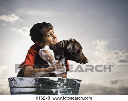 Stock Photo - Smiling boy hugging and bathing dog outdoors on cloudy day. Fotosearch