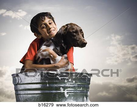 Smiling boy hugging and bathing dog outdoors on cloudy day View Large Photo Image Stock Photo - Smiling boy hugging and bathing dog outdoors on cloudy day. Fotosearch