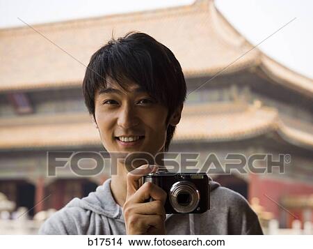 Picture - Teenage boy outdoors with digital camera smiling. Fotosearch