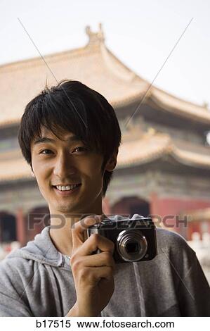 Stock Photography - Teenage boy outdoors with digital camera smiling. Fotosearch