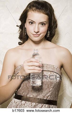 Teenage girl holding bottled water smirking View Large Photo Image Stock Image - Teenage girl holding bottled water smirking. Fotosearch